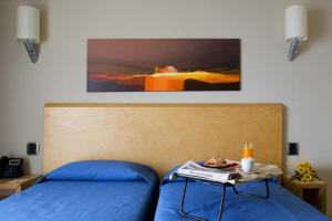 Un dormitorio con una cama azul con una mesa. en Taormina Panoramic Hotel, en Taormina