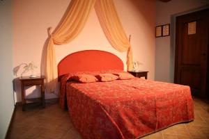 Agriturismo Vecchio Gelso في Ortezzano: غرفة نوم بسرير ولحاف احمر