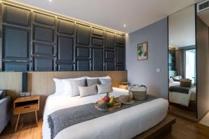 een slaapkamer met een groot bed met een fruitschaal erop bij Wyndham Grand Nai Harn Beach Phuket in Nai Harn Beach