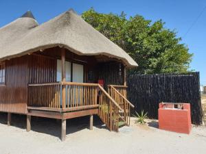 a small hut with a thatched roof and a fence at Honne-Pondokkies in Hondeklipbaai