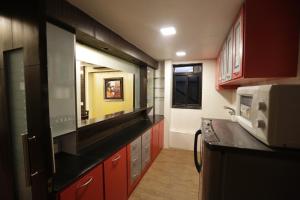 a kitchen with red cabinets and a microwave at Hotel Metro Palace in Mumbai