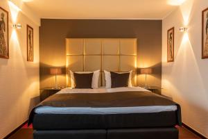 a bedroom with a large bed with two lamps at Mauritius Hotel & Therme in Cologne