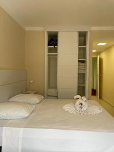 a bedroom with a white bed with a stuffed animal on it at Hotel Cavalinho Branco - Aptos 241 e 317 in Águas de Lindóia