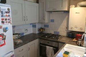 a kitchen with white cabinets and a stove top oven at Cathedral View Cottage, Canterbury in Kent