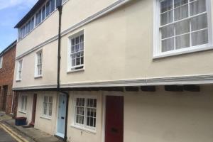 a white building with a red door on a street at Cathedral View Cottage, Canterbury in Kent