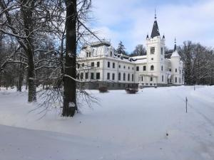 a large white house with a snow covered yard at Stamerienas Apartamenti in Stāmeriena