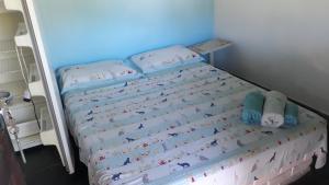a small bed in a bedroom with a blue wall at Alebelhinha Residencial Camburi Pousada in Camburi