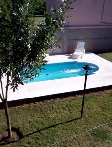 Victorica的住宿－Cabañas bajos medanales，房屋旁带椅子的游泳池