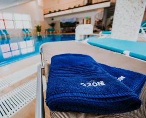 a blue towel is on a bed next to a swimming pool at Hotel O3zone - Mountain Spa & Conference in Băile Tuşnad