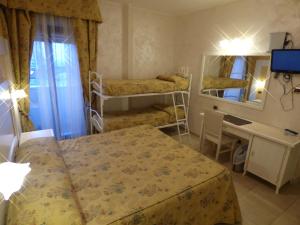 a room with two beds and a desk and a mirror at Hotel Diplomat Palace in Rimini