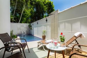 a patio with a table and chairs and a pool at Calamar Flats - Frente à Praia do Jabaquara in Paraty