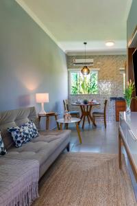 a living room with a couch and a dining room at Calamar Flats - Frente à Praia do Jabaquara in Paraty