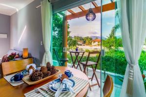 a dining room with a table and a large window at Calamar Flats - Frente à Praia do Jabaquara in Paraty