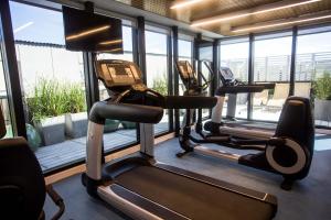 a gym with three tread machines and windows at Hotel Marqués del Mar in Mar del Plata