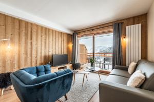 a living room with a couch and a tv at Residence Hameau de Clotaire Alpe d'Huez - by EMERALD STAY in L'Alpe-d'Huez