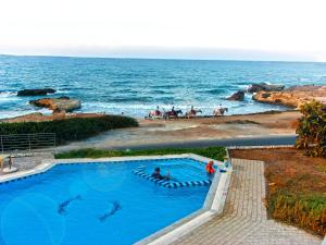 una piscina vicino all'oceano con persone sulla spiaggia di Romantica Beach a Hersonissos