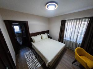 niewielka sypialnia z łóżkiem i żółtym krzesłem w obiekcie Vikendica Aleksandrović Ježevac w mieście Topola