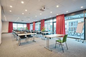 una sala de conferencias con mesas, sillas y cortinas rojas en Jugendherberge Oldenburg "DJH Mitgliedschaft erforderlich - membership required" en Oldenburg
