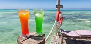 two drinks sitting on a table with the ocean in the background at Reef & Beach Resort - Spa Jambiani in Jambiani