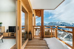a room with a balcony with a view of mountains at Residence Hameau de Clotaire Alpe d'Huez - by EMERALD STAY in L'Alpe-d'Huez