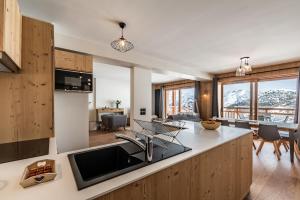 een keuken en een woonkamer met uitzicht op de bergen bij Residence Hameau de Clotaire Alpe d'Huez - by EMERALD STAY in L'Alpe-d'Huez