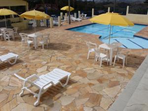 a group of chairs and umbrellas next to a pool at Pousada Campestre Estância São Domingos in Serra Negra