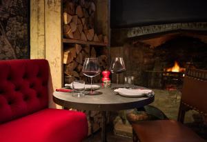 a table with two wine glasses and a fireplace at The Double Red Duke, Cotswolds in Clanfield