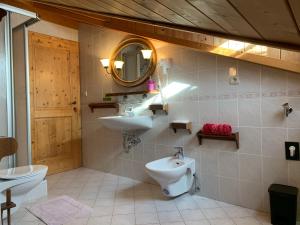 a bathroom with a sink and a toilet and a mirror at Bachlaufen Haus in Sesto