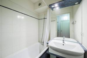 La salle de bains blanche est pourvue d'un lavabo et d'une douche. dans l'établissement Residence Les Chalets d'Aurouze - maeva Home, à La Joue du Loup