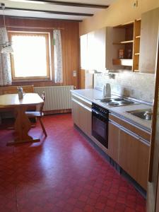a kitchen with a stove and a sink and a table at Ferienwohnung Auszeit mit viel Ruhe und Natur in Untrasried