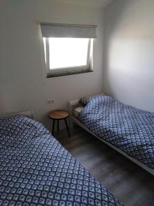 twee bedden in een kleine kamer met een raam bij De Maplerik in Oirlo