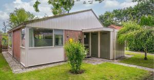 een klein huis met een garage in een tuin bij Rekerlanden 119 de Amandelbloesem in Schoorldam