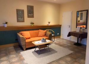 a living room with an orange couch and a table at Hotel Krasemann in Isselburg