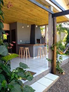 eine Außenküche mit einer Bar und Hockern in der Unterkunft Happy House - Casa ideal para grupos na cidade dos Canyons in Praia Grande