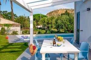 une terrasse avec une table, des chaises et une piscine dans l'établissement Residence Salinelle Beach Villa Lipari 1, à Lascari
