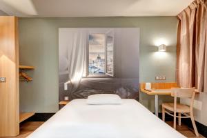 1 dormitorio con cama blanca y escritorio en B&B HOTEL Louveciennes en Louveciennes