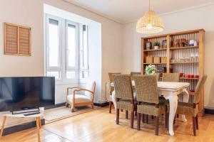 a dining room with a table and chairs and a tv at Apartamento KUIA con vistas frontales a la Ría de Bilbao cerca del metro in Erandio