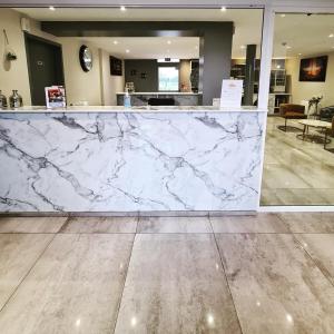 a marble counter in a lobby with a counter top at Hotel Les Beaux Soleils in Osny