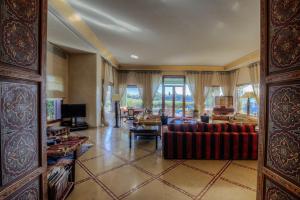 a living room with a couch and a tv at Villa MEZIANE avec piscine privée en première ligne du golf d'Amelkis in Marrakech