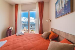 a bedroom with a large orange bed and a window at Villas Valentina in Bijela