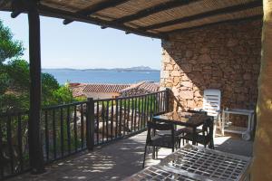um pátio com uma mesa e cadeiras e o oceano em Residence I Cormorani Bis em Baja Sardinia