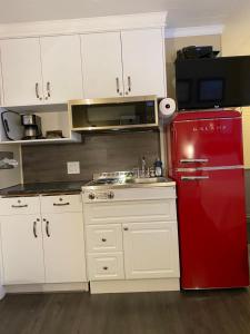 a kitchen with a red refrigerator and white cabinets at Oreland Motel in Flin Flon