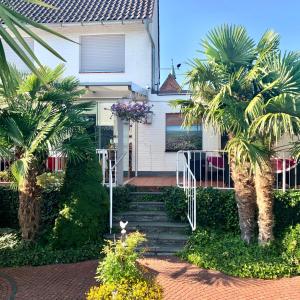 ein weißes Haus mit Palmen davor in der Unterkunft Hotel Krasemann in Isselburg