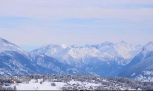 una cordillera cubierta de nieve con una ciudad en primer plano en Des Masques en Anzère