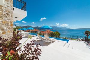 a pool with chairs and umbrellas overlooking the ocean at Villas Valentina in Bijela
