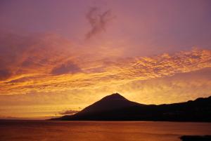 ein Berg unter einem wolkigen Himmel bei Sonnenuntergang in der Unterkunft One bedroom appartement with sea view terrace and wifi at Lajes Do Pico in Lajes do Pico