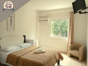 Un dormitorio con una cama y una silla y una ventana. en Hotel Moinho da Luz - Próximo a Lajeado, en Arroio do Meio