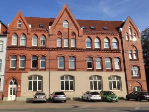 een groot bakstenen gebouw met auto's geparkeerd voor het bij Apartment an der Altstadt (#6) in Hameln