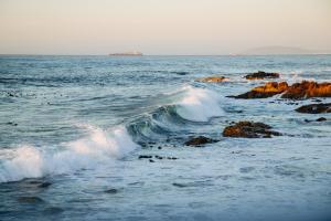 a wave in the ocean with rocks in the water at ALBATROSS SUITE in Cape Town