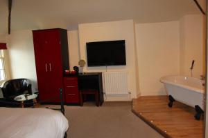 a bedroom with a bed and a tub and a television at The Olive Branch in Ilfracombe